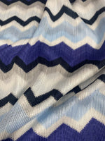 Close-up of blue, purple, beige geometric zigzag patterned woven fabric with textured knit mesh design