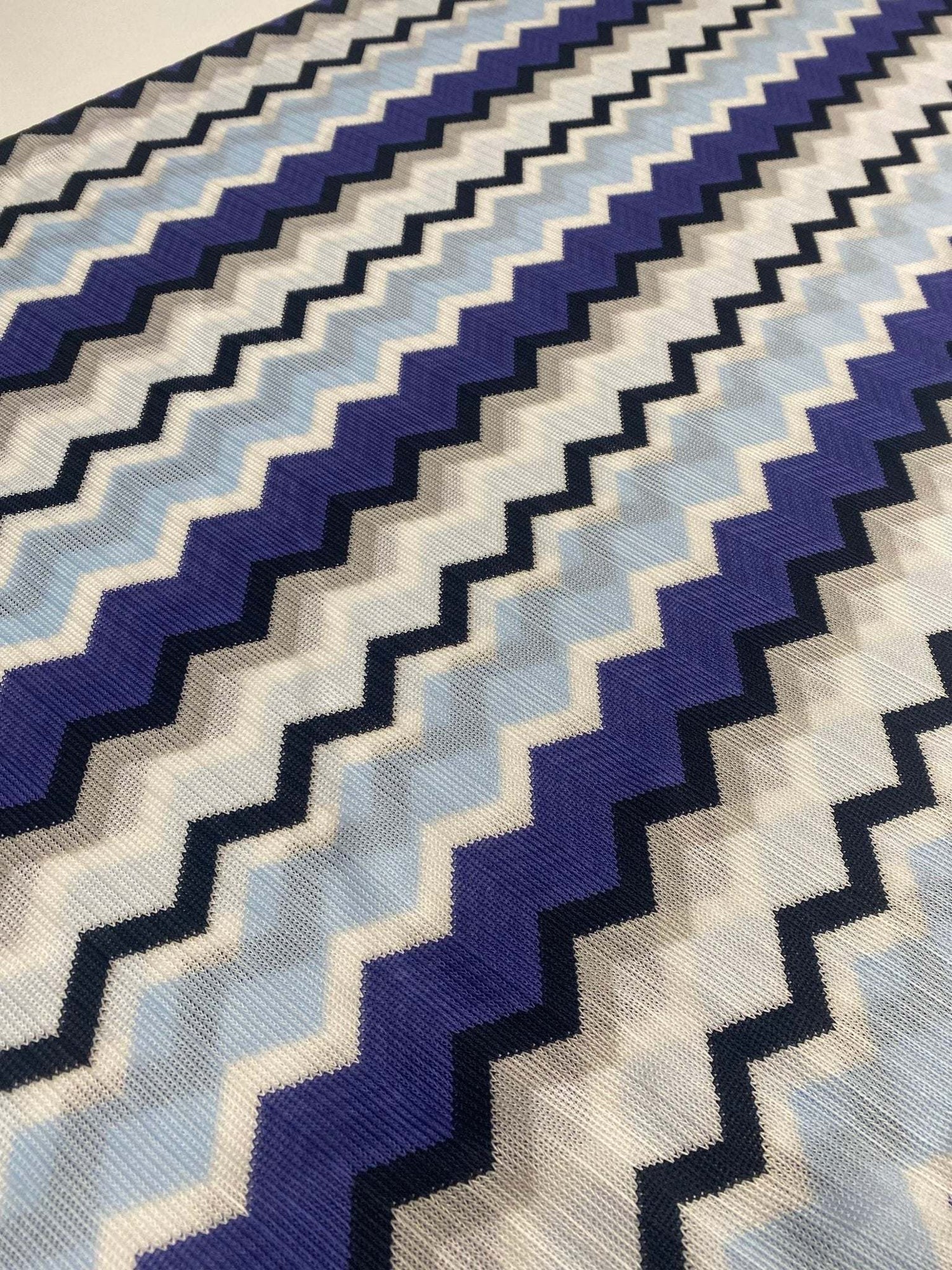 Blue, purple, and beige geometric zigzag patterned fabric with woven texture for sewing projects