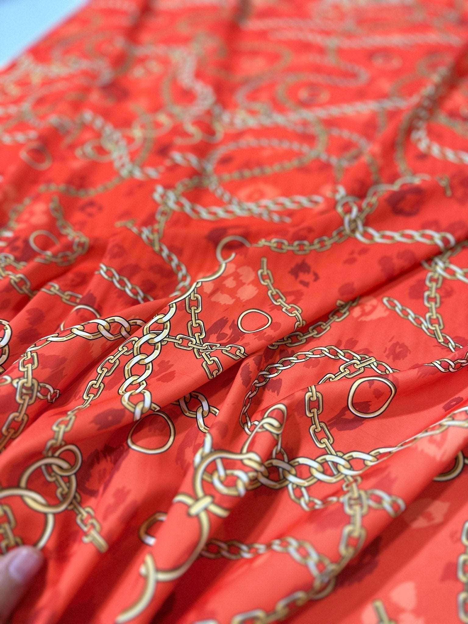 Orange fabric with gold chain design pattern close-up