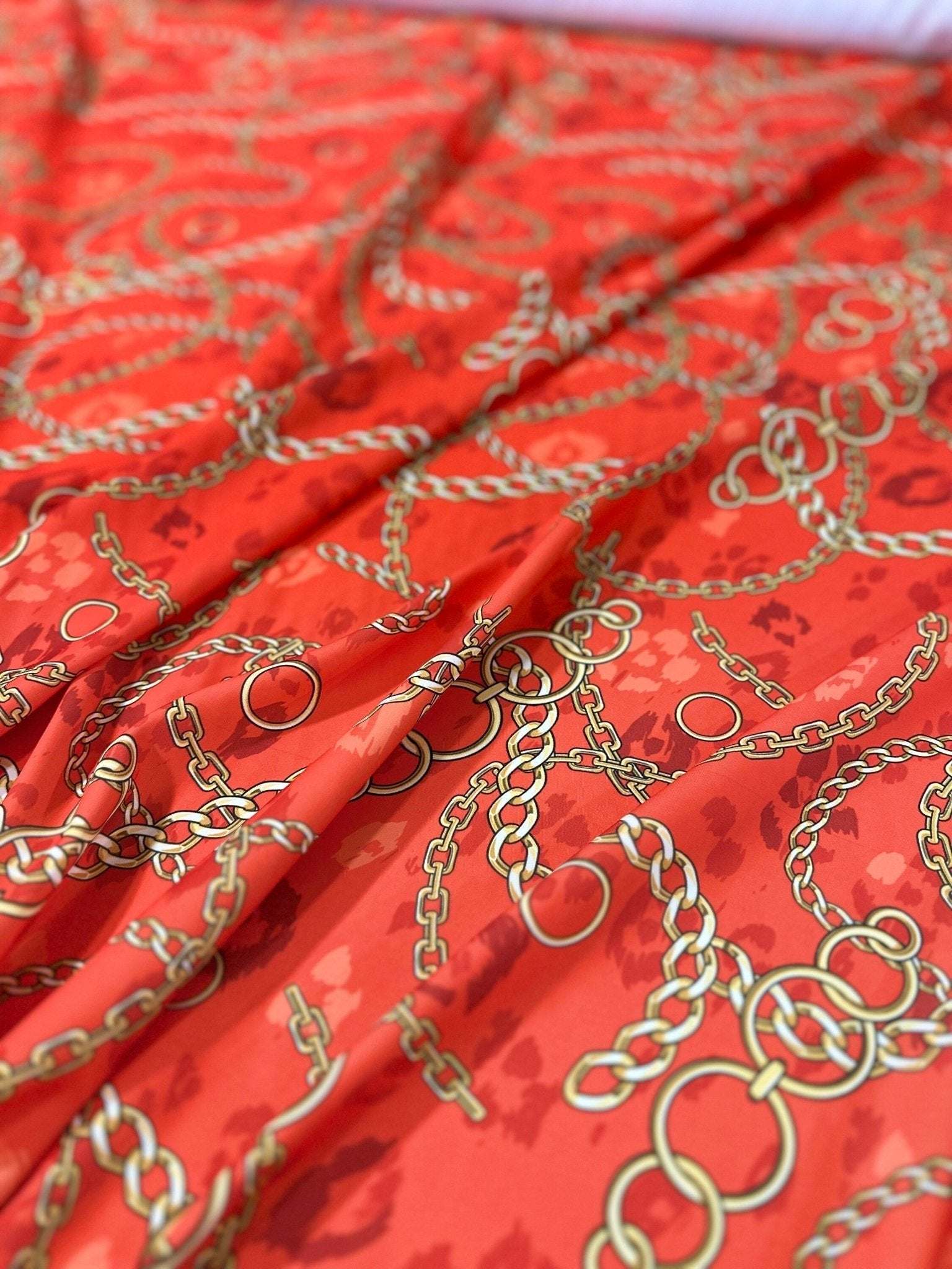 Orange fabric with gold chain design pattern, fabric width 150cm, vibrant and luxurious textile for sewing projects