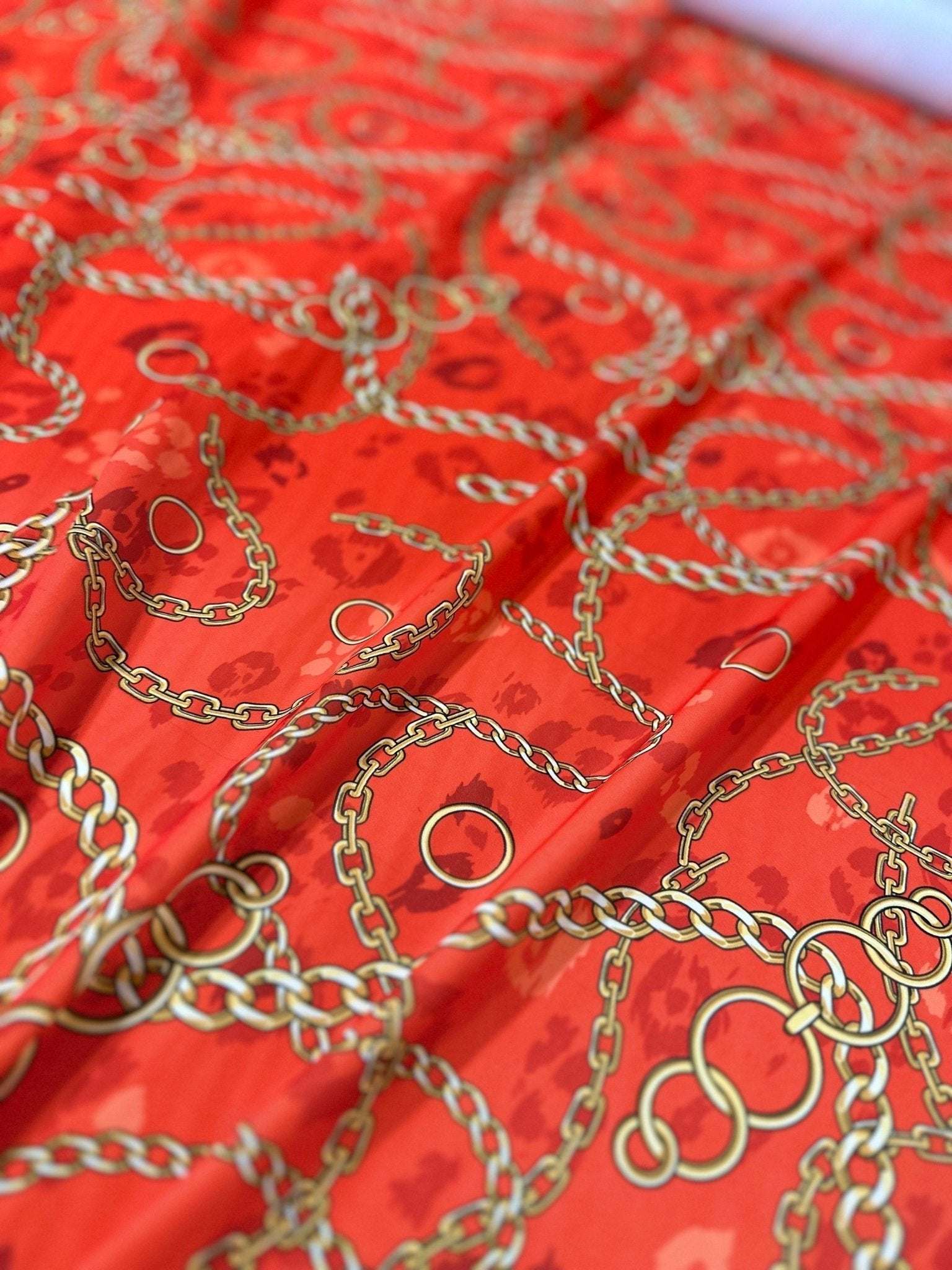 Orange fabric with gold chain design pattern by the yard