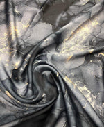 Gray tie dye fabric with gold accents in a swirling pattern, ideal for fashion and craft projects