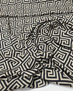 Black and beige Greek key patterned fabric with 150cm width, shown draped and folded.