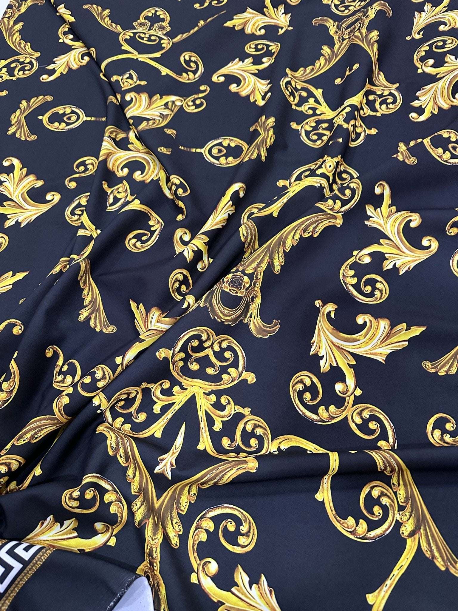 Black fabric with gold Greek key and ornate pattern design textile