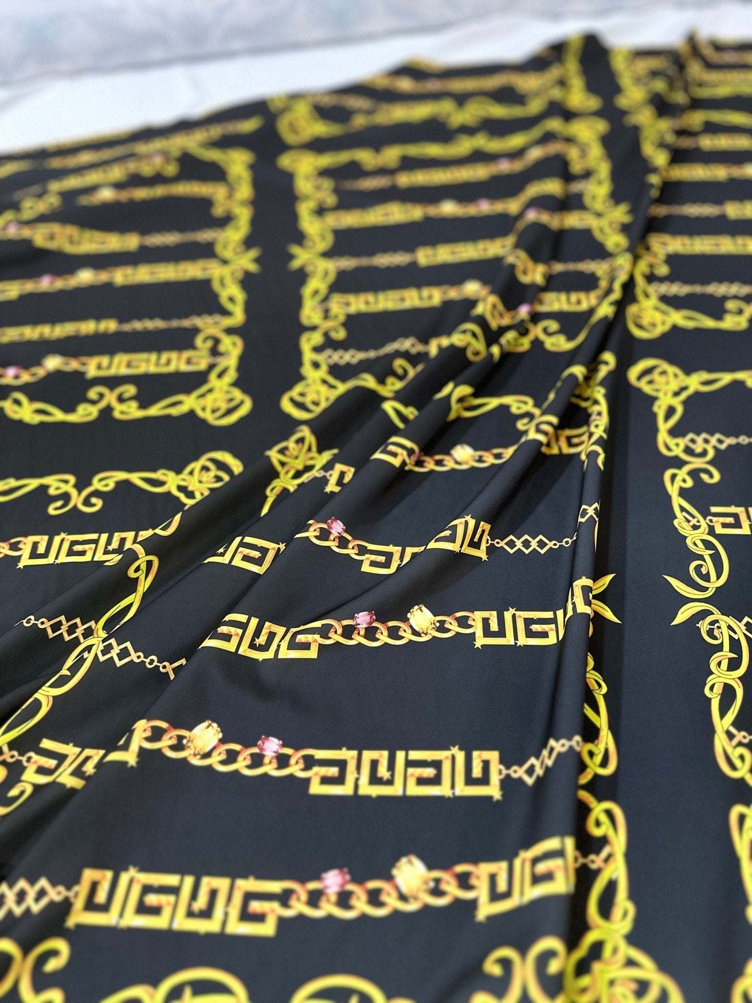Black fabric with gold Greek key chain pattern for upholstery and fashion projects