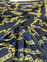 Close-up of black fabric with gold Greek key and chain pattern design