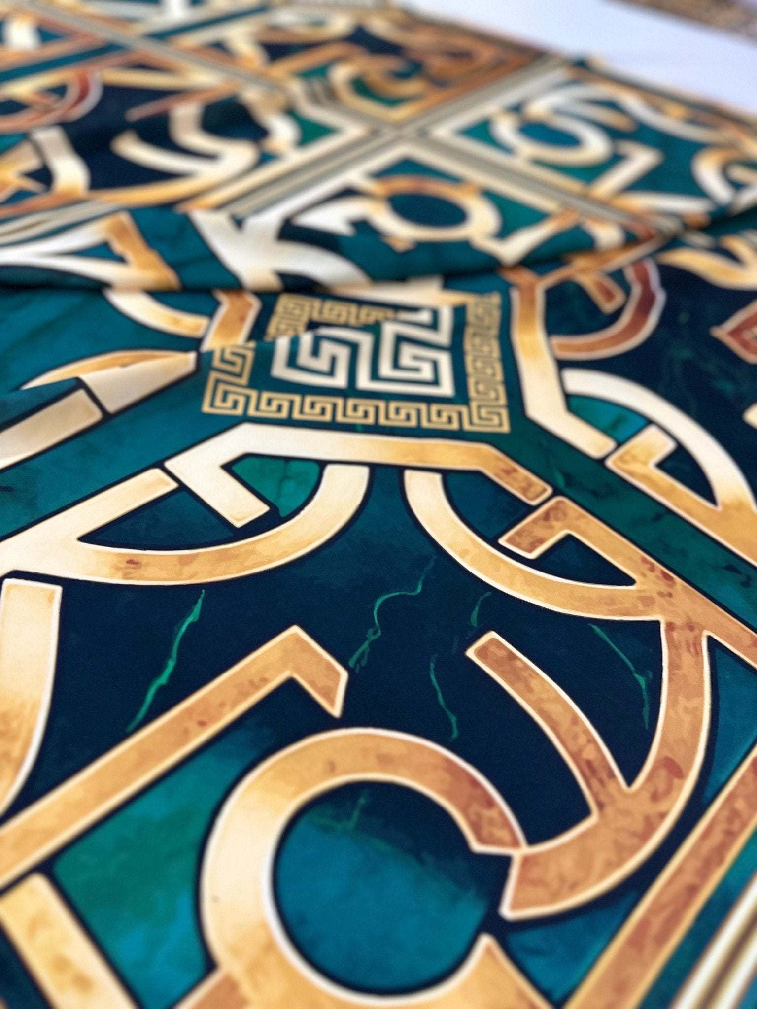close-up of green gold crepe silky fabric with Greek key pattern and smooth texture