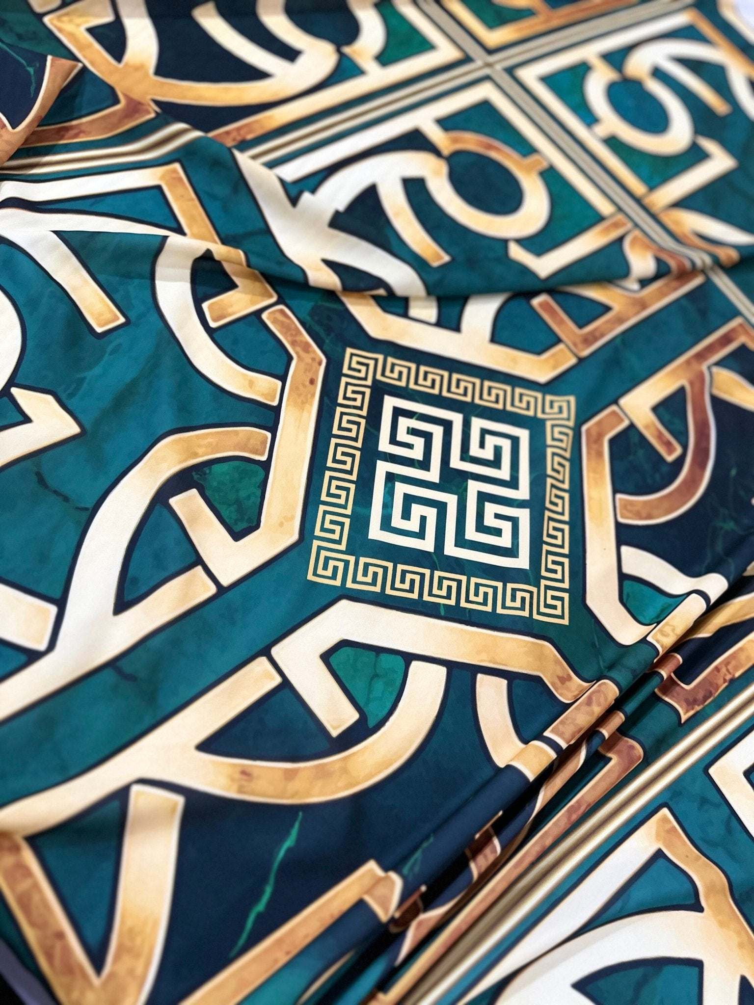 Green gold crepe silky fabric with Greek key pattern in teal and gold colors, smooth texture, and 150cm width.