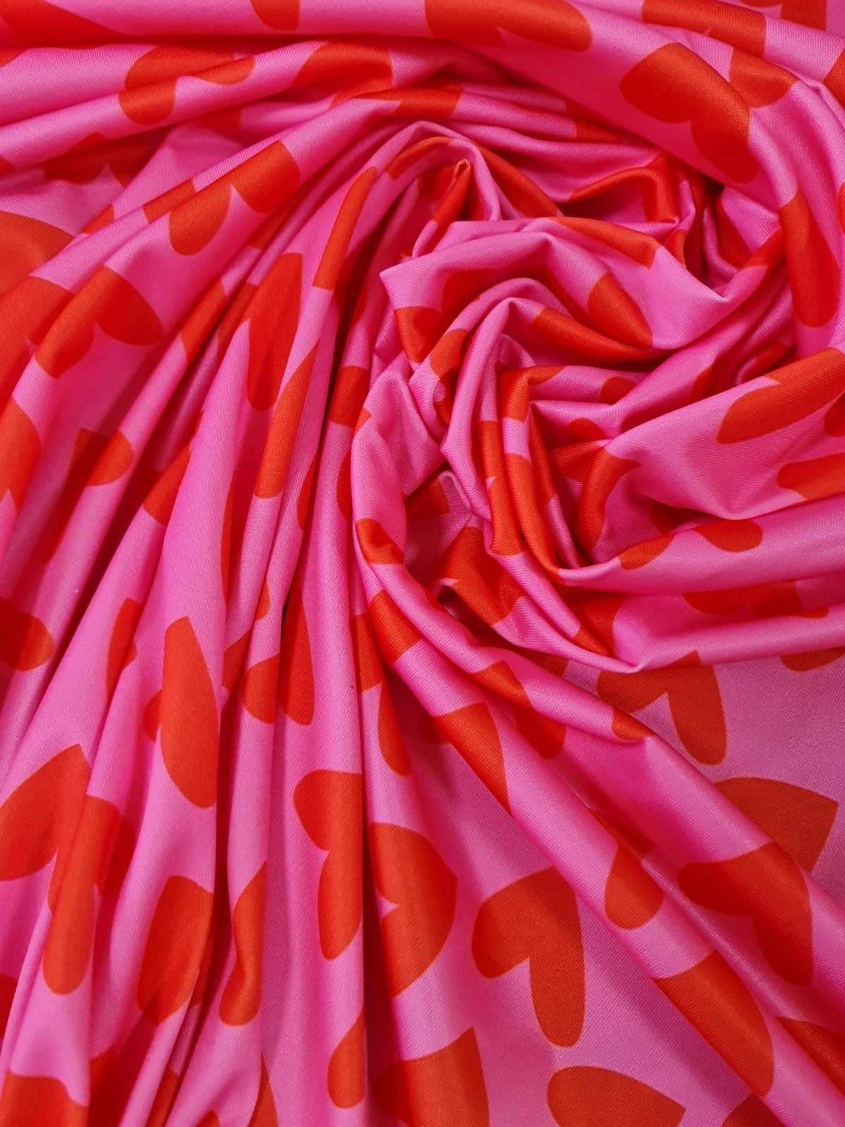 Pink cotton fabric with red heart print pattern, soft and ideal for sewing projects