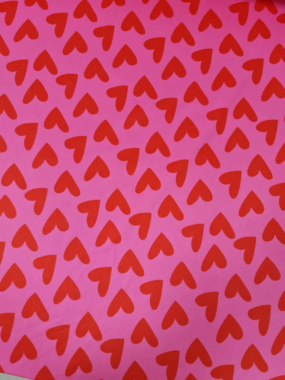 Pink cotton fabric with red heart print pattern for crafting and sewing projects