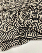 Greek Key Design Fabric in black and beige geometric pattern, 150cm wide, draped on a surface for upholstery and crafts