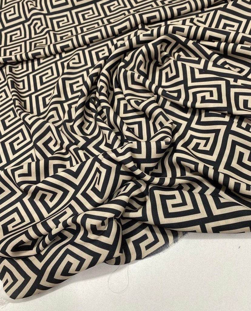 Greek Key Design Fabric in black and beige geometric pattern, 150cm wide, draped on a surface for upholstery and crafts