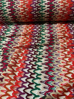 Roll of vibrant multicolor zigzag knit jersey fabric with chevron pattern and soft texture