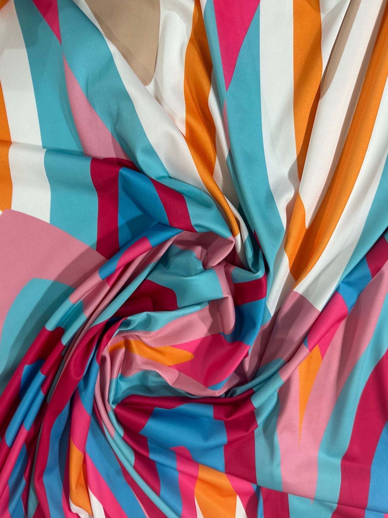 Soft geometric print fabric with colorful modern triangular and striped patterns in pink, blue, orange, and beige tones