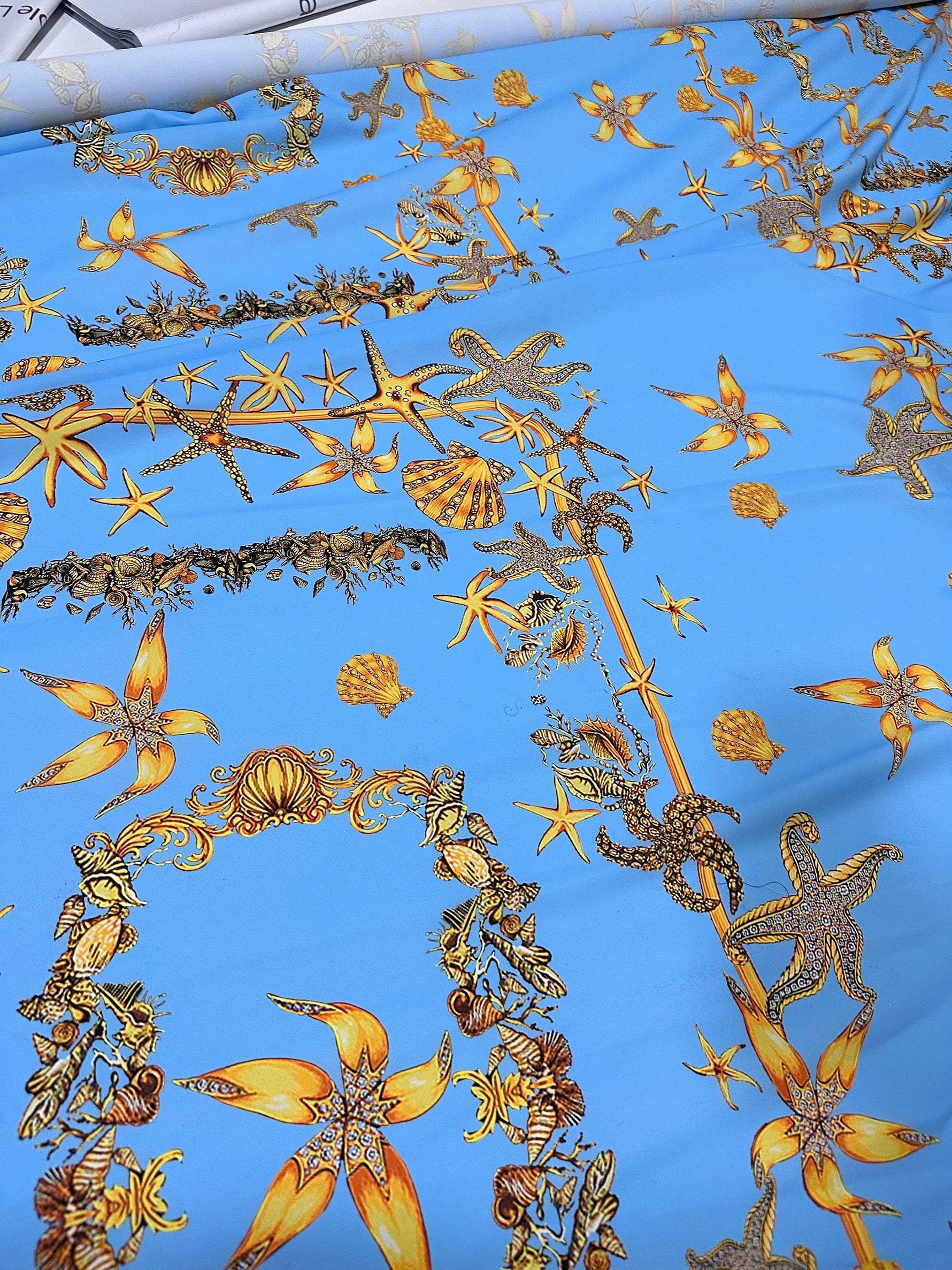 Blue fabric with detailed golden sea shell and starfish pattern for coastal-themed projects