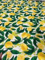 White cotton fabric with vibrant yellow lemon pattern and green leaves for crafting and home décor