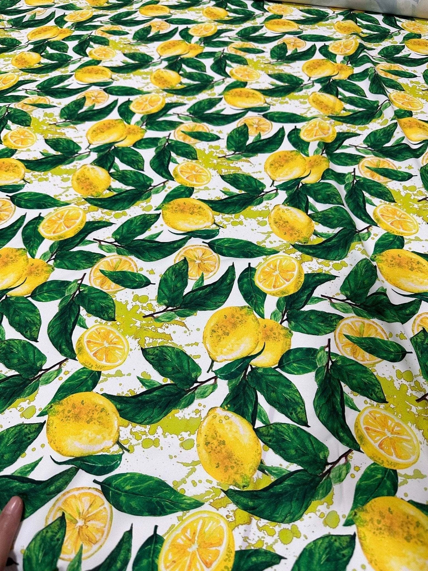 White cotton fabric with vibrant yellow lemon pattern and green leaves for crafting and home décor