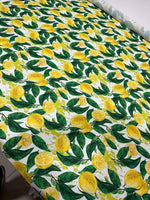 Cotton fabric with vibrant lemon pattern and green leaves on white background