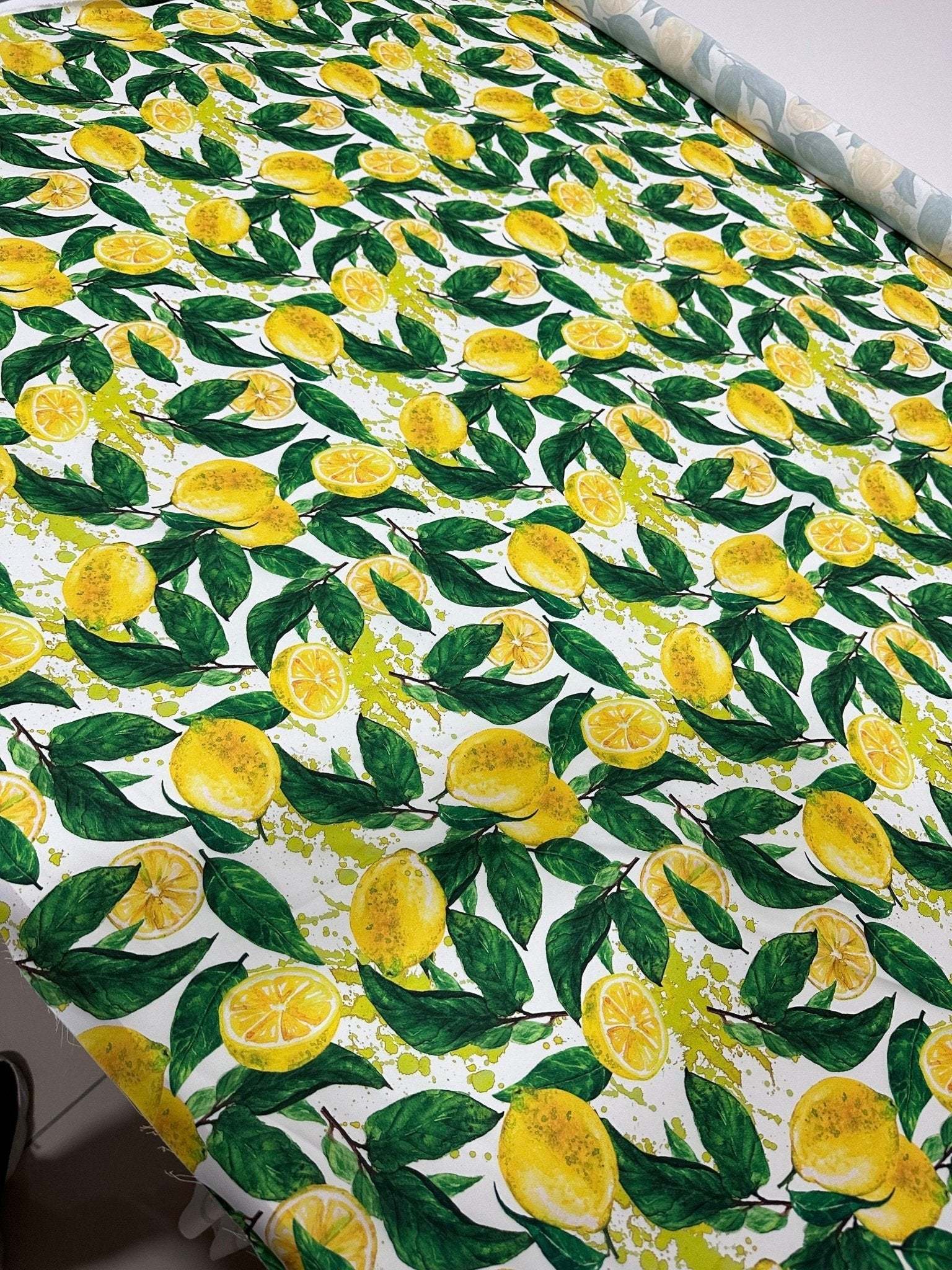 Cotton fabric with vibrant lemon pattern and green leaves on white background