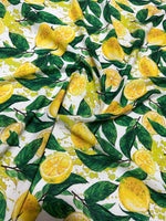 Lemon pattern fabric with yellow lemons and green leaves on white cotton textile