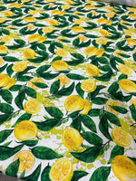 White cotton fabric with vibrant lemon and green leaf pattern for sewing and crafting projects