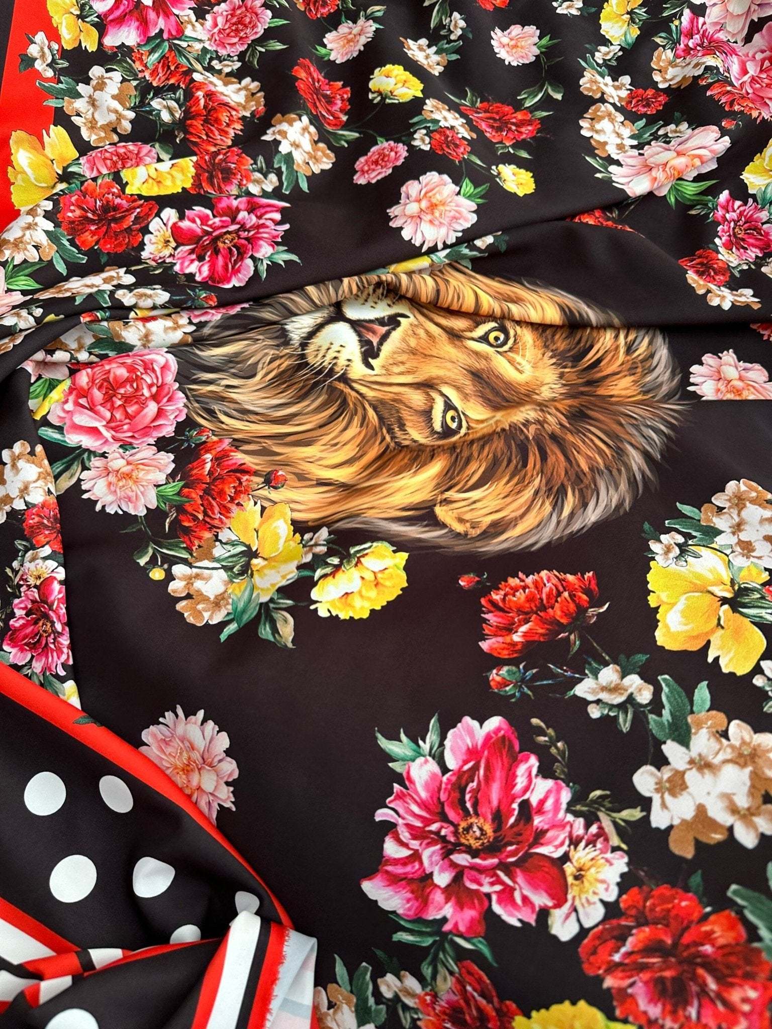 black floral print fabric with vibrant red, pink, yellow flowers and a detailed lion face design