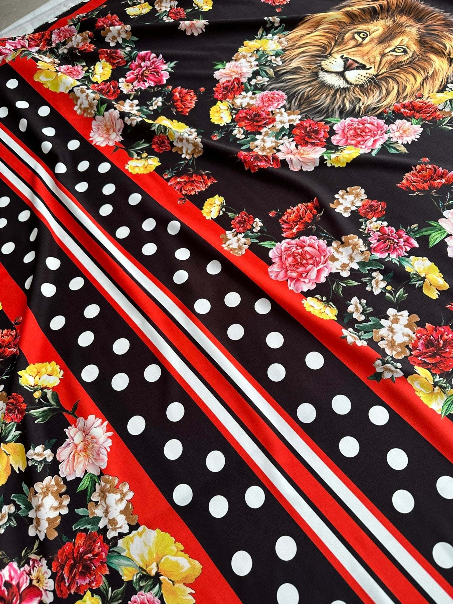 Floral print fabric with colorful flowers, polka dots, stripes, and lion motif on black background