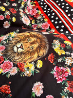 Floral print fabric with vibrant flowers and a lion illustration on black background with red and white striped polka dot border