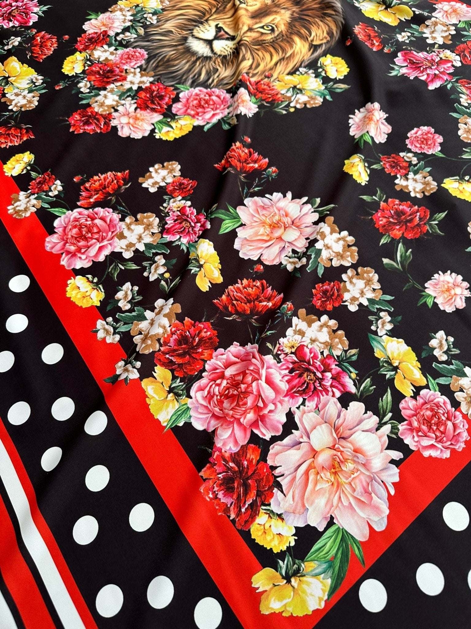 Floral print fabric with vibrant flowers, lion design, red border, and black polka dot background