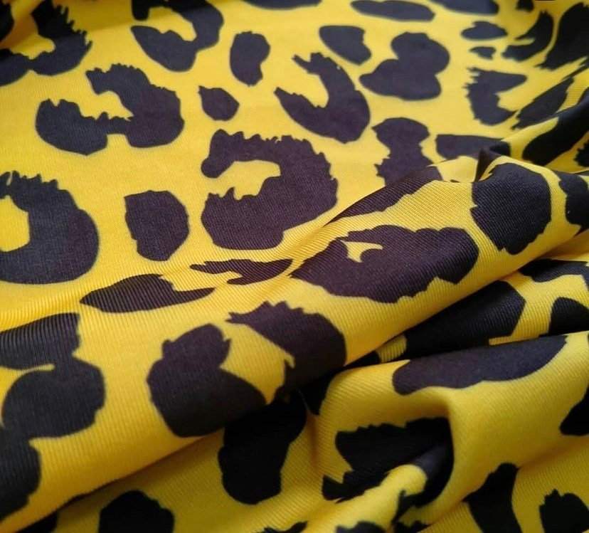 Close-up of yellow leopard pattern stretch fabric with black spots and soft texture