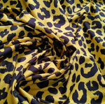 Yellow leopard pattern stretch fabric with black spots in a soft and flexible material