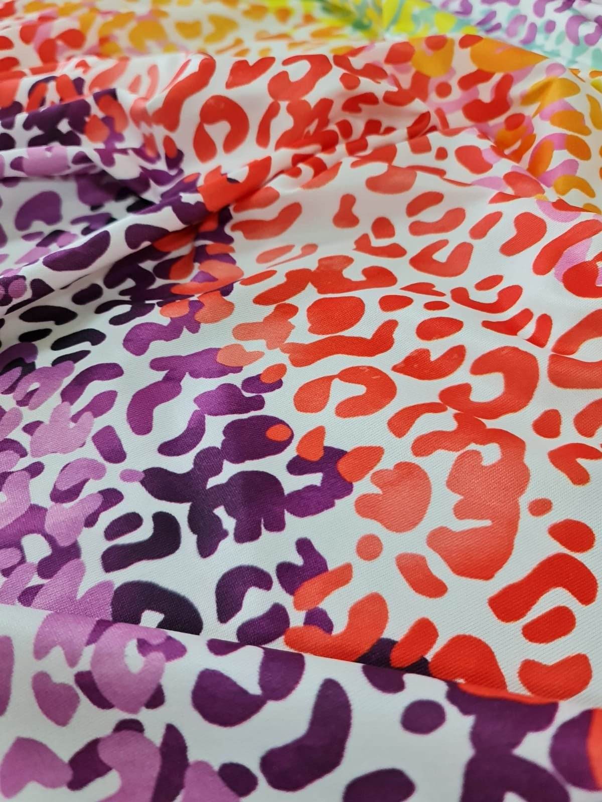 Colorful leopard print fabric with vibrant red, purple, and orange spots on a white background, ideal for sewing projects