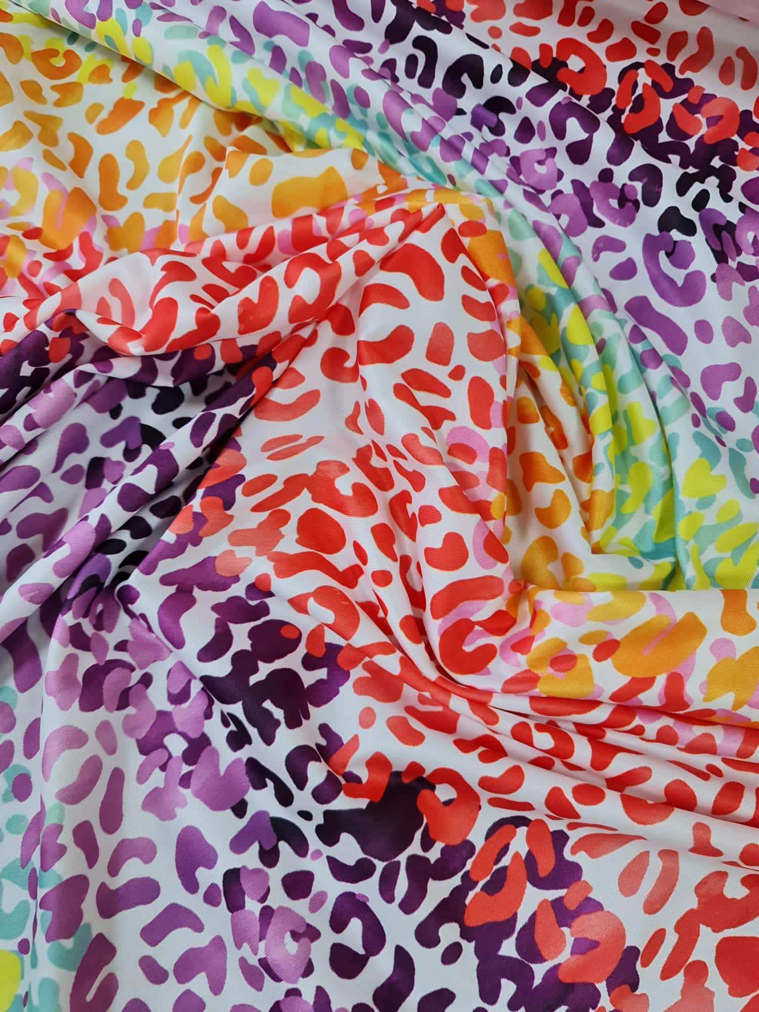 Colorful leopard print fabric with orange, purple, red, and yellow animal pattern for sewing projects