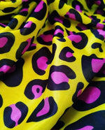 Bright yellow leopard print fabric with bold black and purple animal pattern, soft textured textile for fashion and crafting projects