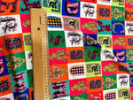 Colorful letter print cotton fabric with intricate designs and a wooden ruler for scale