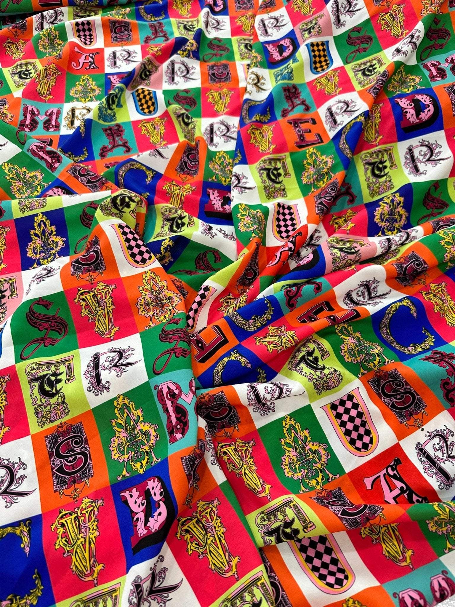 Colorful letter print cotton fabric with various alphabet designs on a checkered background, ideal for sewing and crafting projects