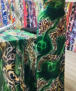 Luxury green leopard print fabric with vibrant emerald swirls and exotic animal pattern displayed in a fabric store