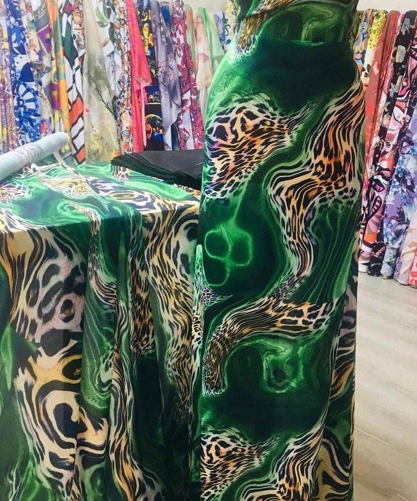 Luxury green leopard print fabric with vibrant emerald swirls and exotic animal pattern displayed in a fabric store