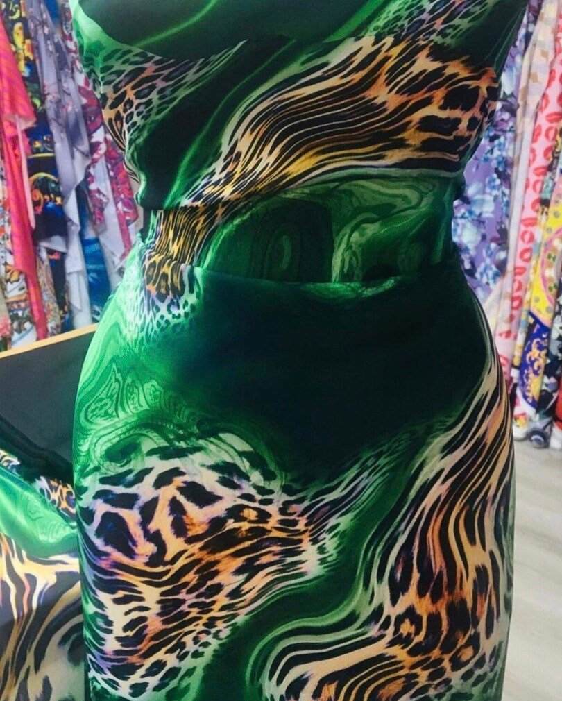 Luxury green leopard print fabric with emerald swirls and exotic animal pattern in a vibrant design