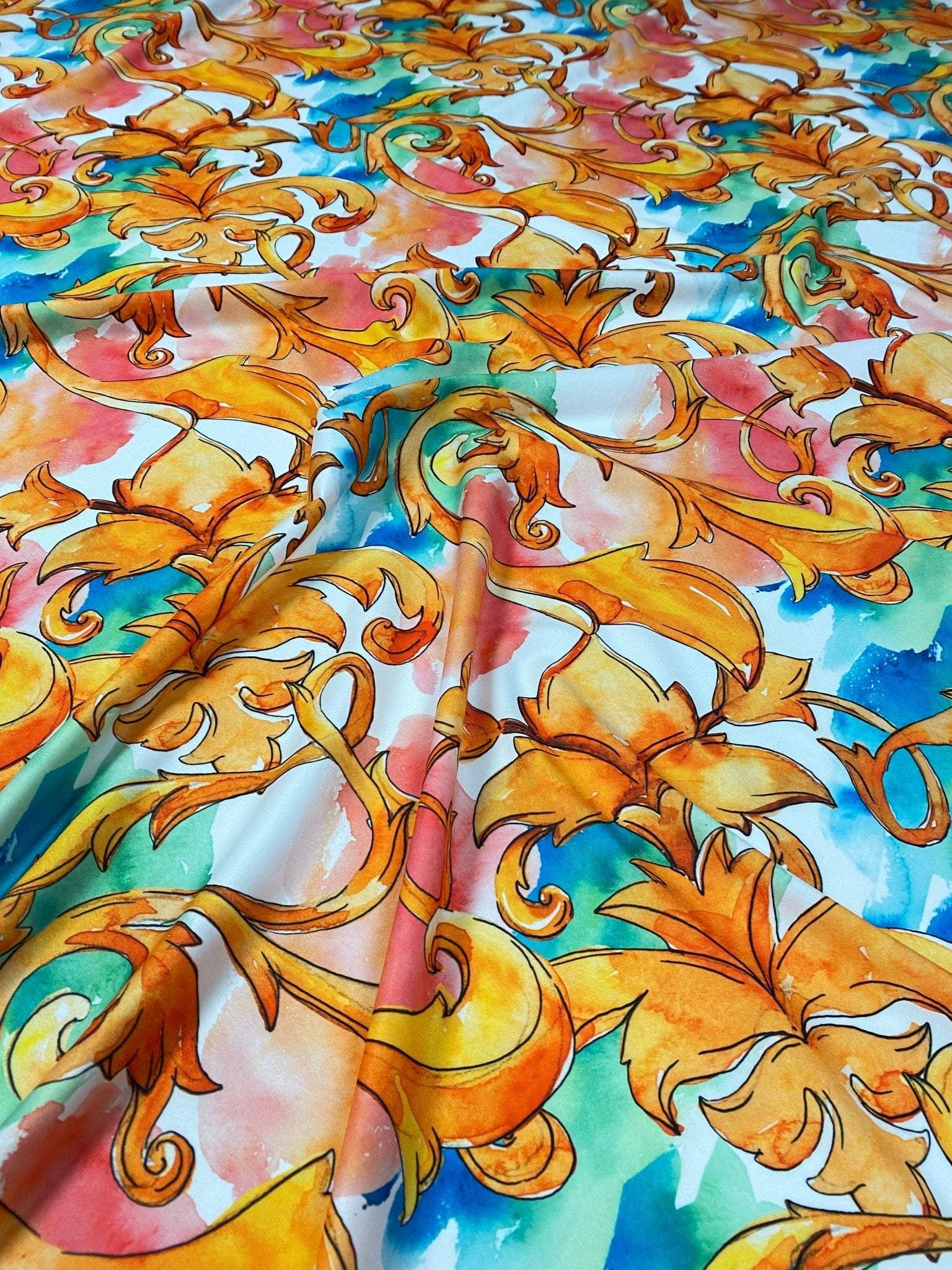Luxury ornate medallion and chain print fabric with vibrant orange, blue, and green colors and intricate design details laid out flat