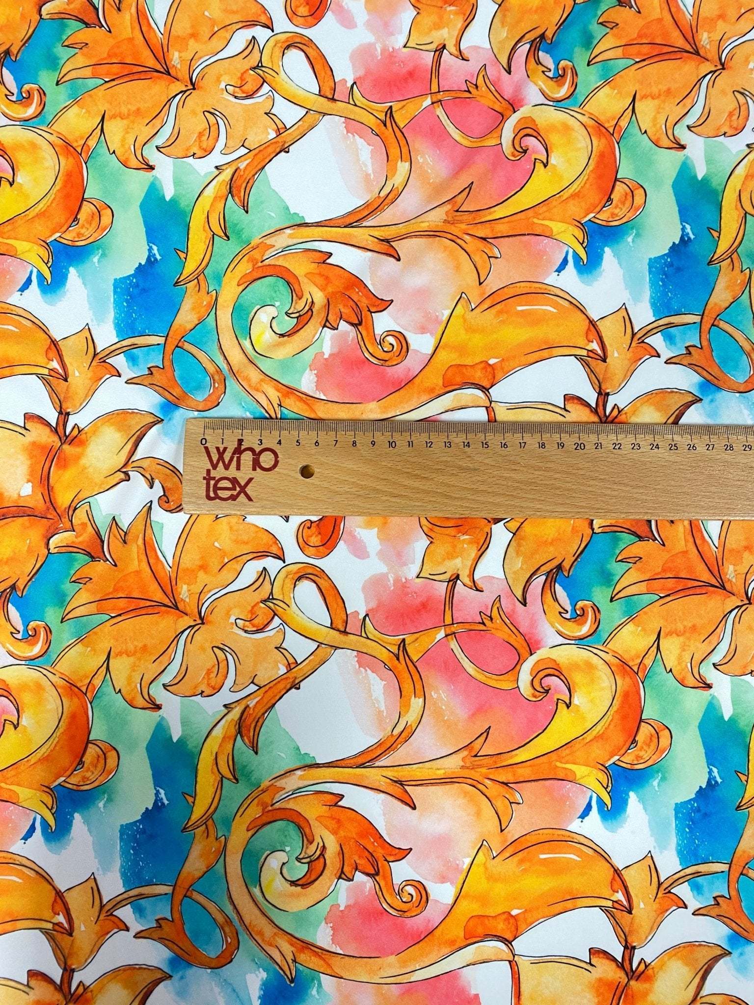 Luxury ornate medallion and chain print fabric with vibrant orange and blue design and ruler for scale