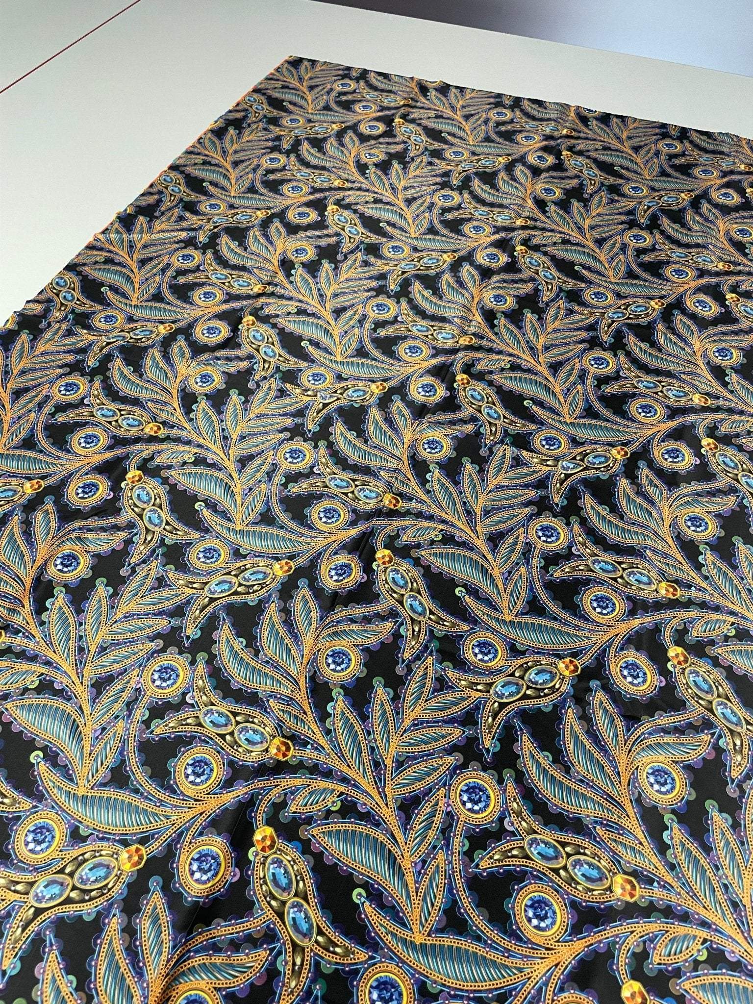 luxury peacock feather fabric with jewel accents showcasing intricate blue and gold feather designs on black background