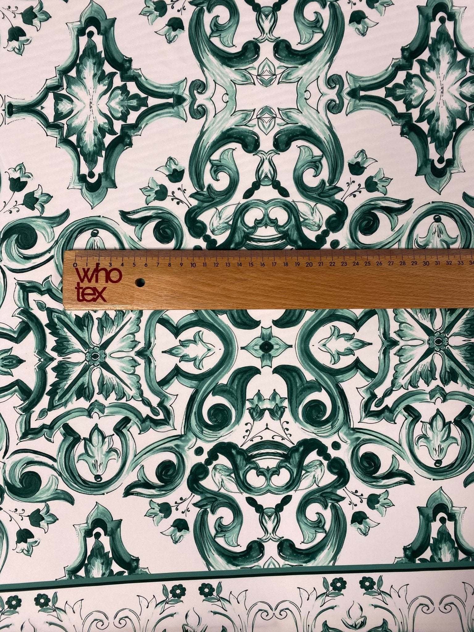 Green and white Majolica pattern fabric with intricate swirl design and ruler for scale