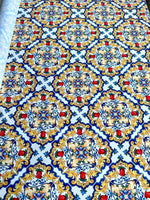 Majolica pattern fabric with vibrant Sicilian print in blue, yellow, and red colors on white background, 150cm wide.