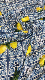 Mediterranean lemon and blue tile print fabric with lemons and floral accents on a blue tiled background