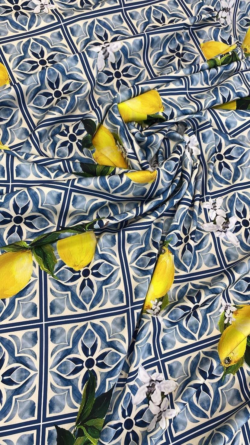 Mediterranean lemon and blue tile print fabric with lemons and floral accents on a blue tiled background