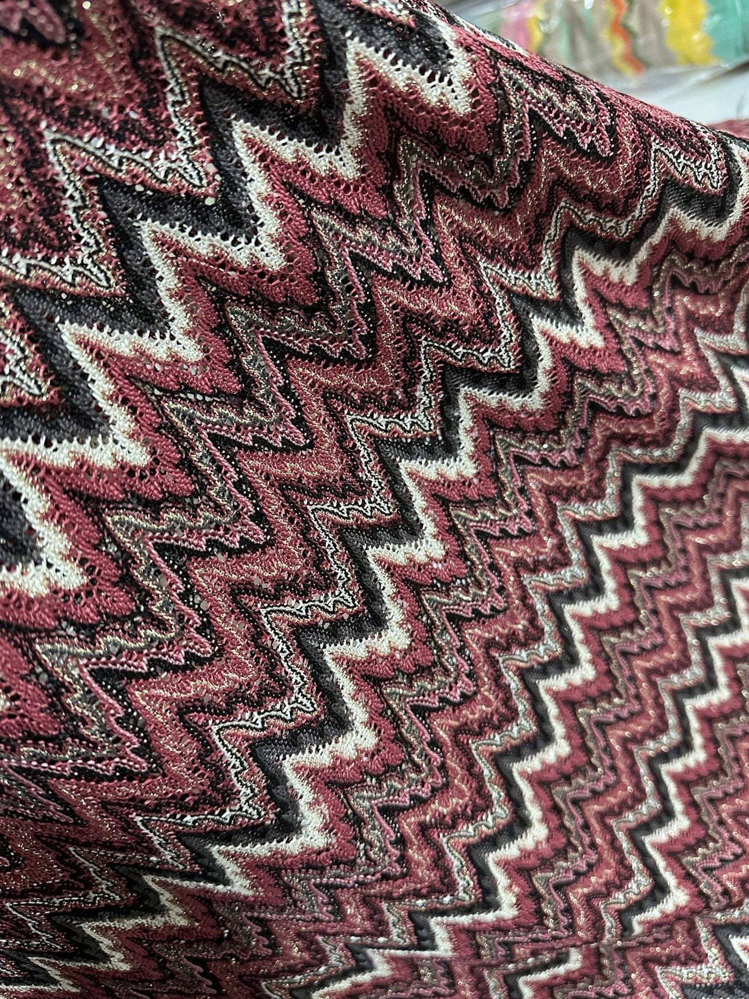 Bordeaux zigzag mesh knit jersey fabric with shiny textured pattern in burgundy and black tones