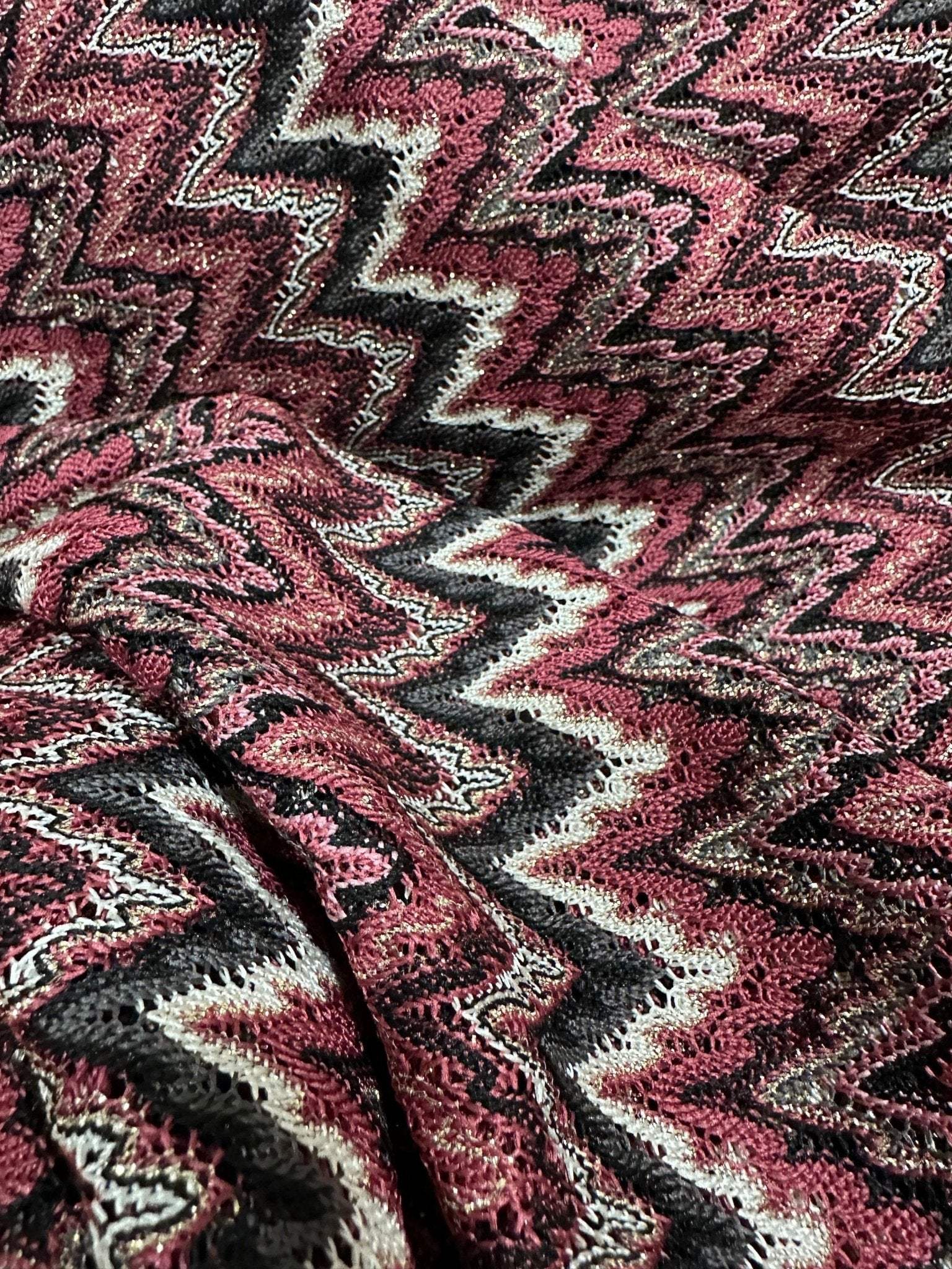 Bordeaux zigzag mesh knit jersey fabric with shiny textured zigzag pattern in burgundy, black, and white tones