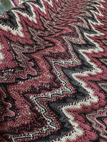 Close-up of Bordeaux Zigzag Mesh knit jersey fabric with shiny zigzag pattern in burgundy, black, and white colors