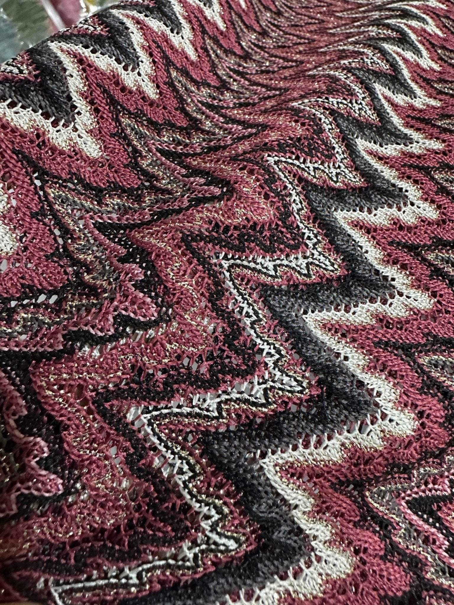 Close-up of Bordeaux Zigzag Mesh knit jersey fabric with shiny zigzag pattern in burgundy, black, and white colors